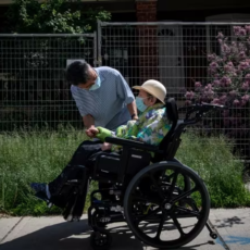 Tenant of long term nursing home in wheelchair with attendant
