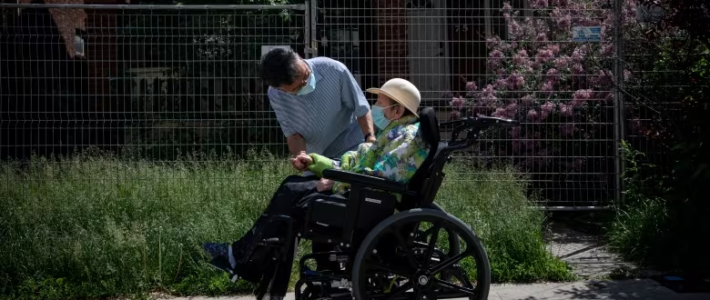 Tenant of long term nursing home in wheelchair with attendant